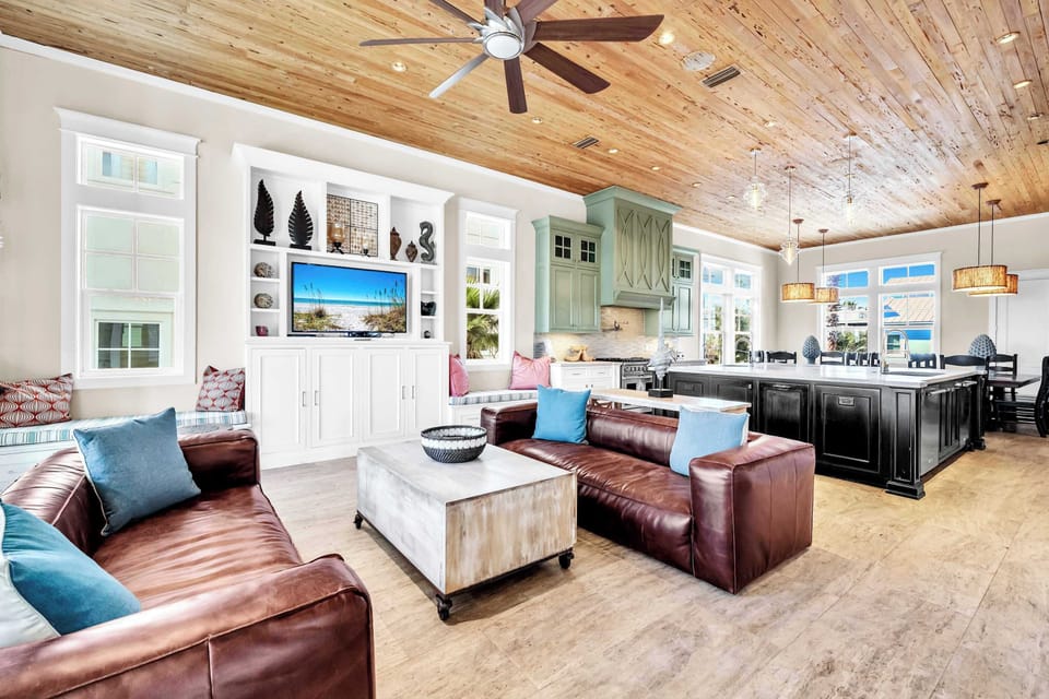 The Open Floor Plan Main Living Area Features Two Stunning Chestnut Leather Couches With Patio Access