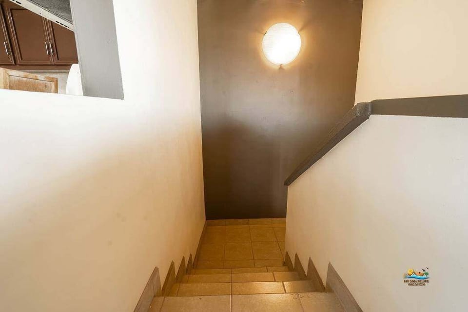 The staircase leads down from the main entrance to the first-floor bedrooms and living areas, where a private patio opens directly onto the beach — no streets to cross, just sand and sea .