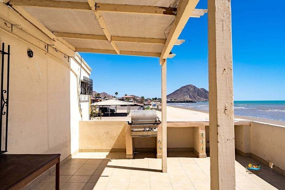 A sliding glass door in the living room opens to a private patio with chairs and a round metal table — offering direct beach access and ocean views for outdoor dining or morning coffee .