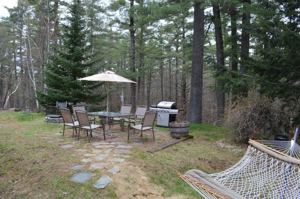 Yard with patio set, grill, fire pit and hammock. 