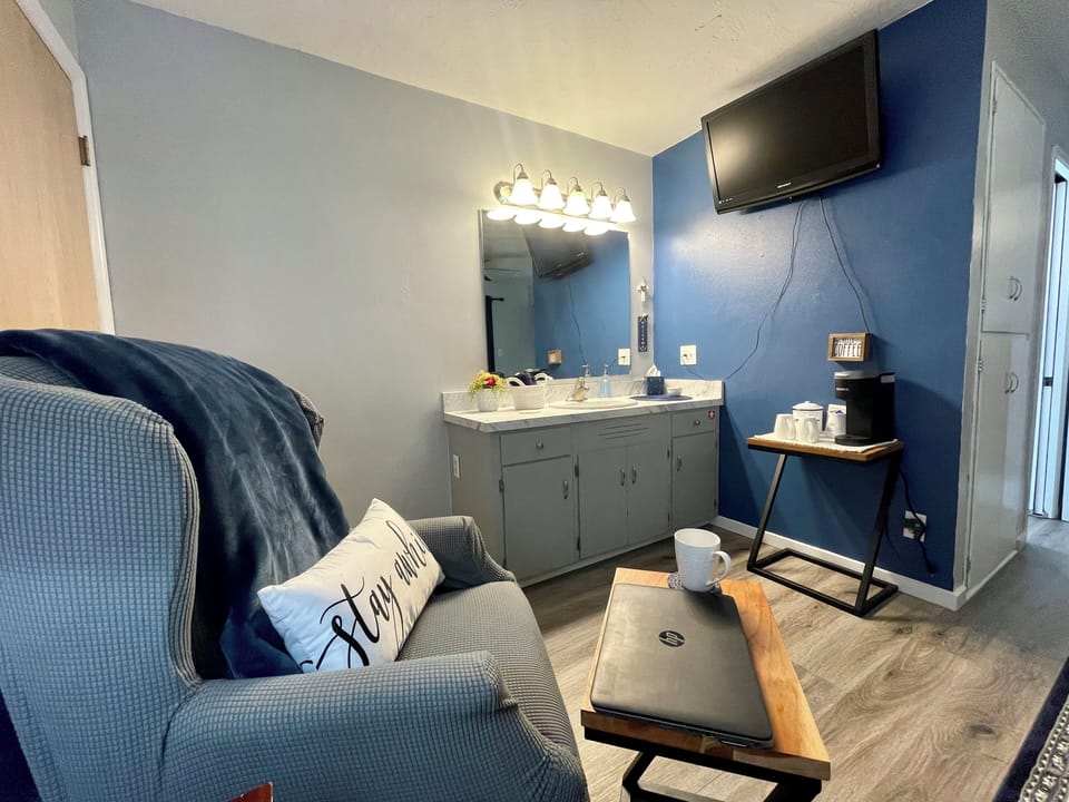 Seating area with a small table. Coffee bar with sugar/creamer. Vanity with sink