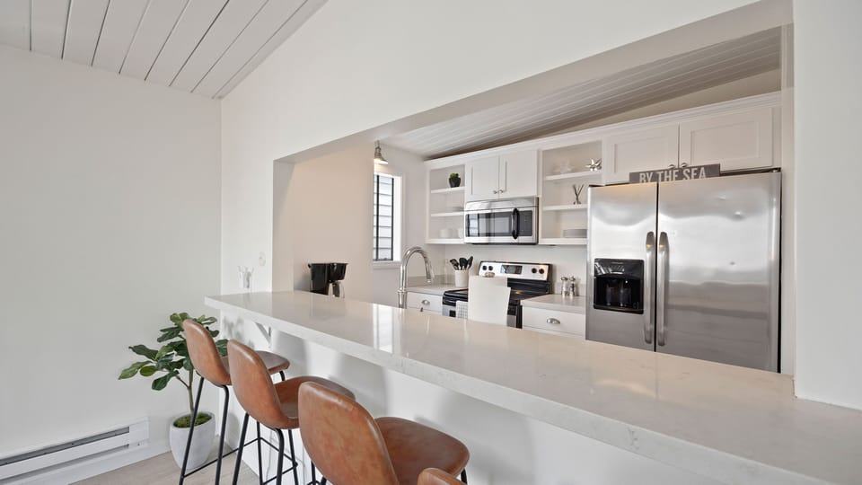 Kitchen opens to Living Area. Counter height bar stools set for casual dining