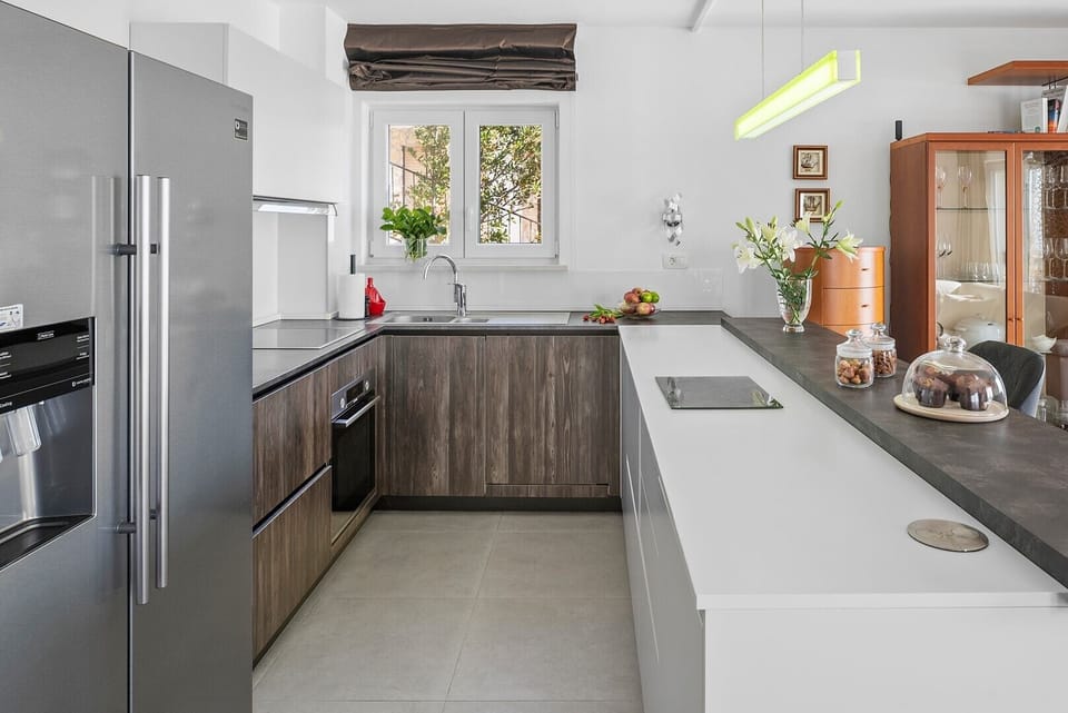 A fully equipped kitchen boasts sleek, wooden cabinetry, integrated appliances, and a central white counter perfect for additional prep space
