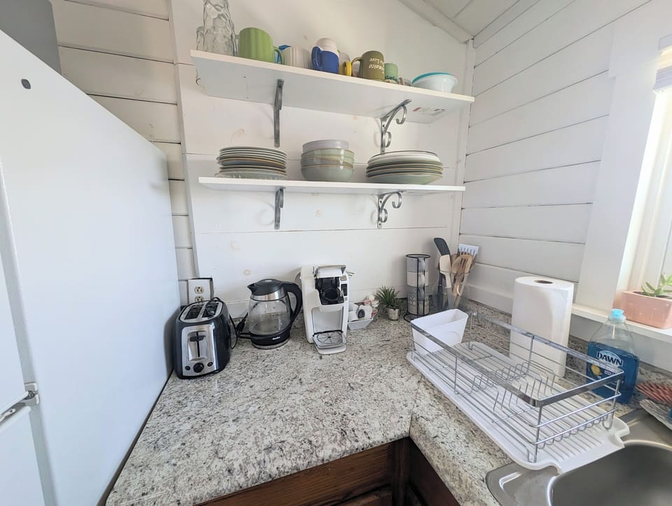 Full kitchen equipped with keurig, pots, pans, blender, cooking utensils.