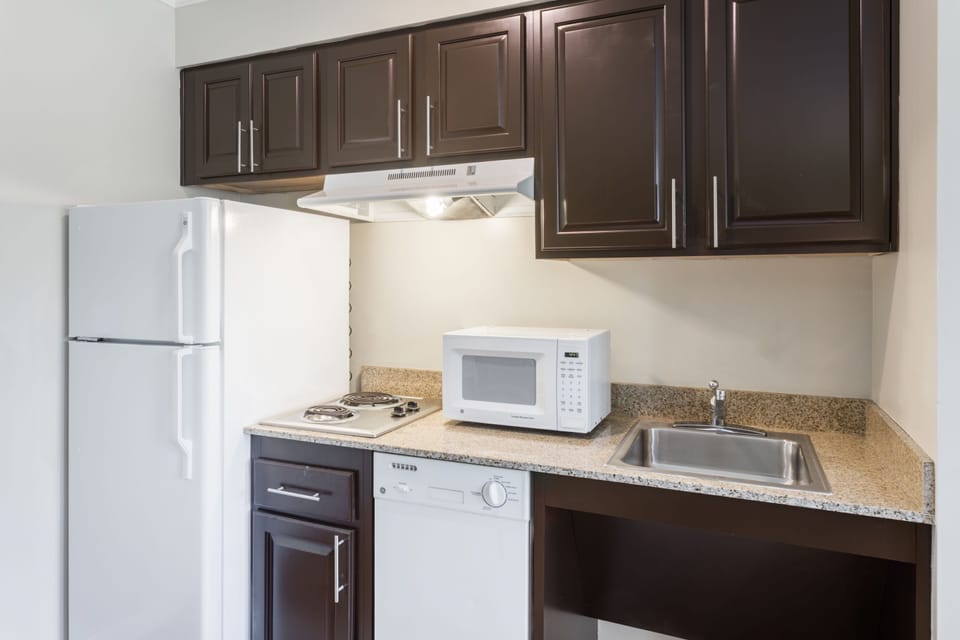Fully equipped kitchen with refrigerator, microwave, cooktop, and counter seating.