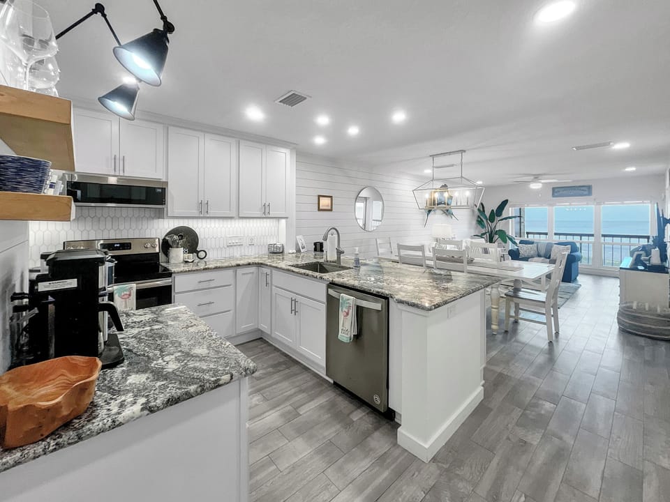 View coffee bar, kitchen, dining, and living room from entry foyer.