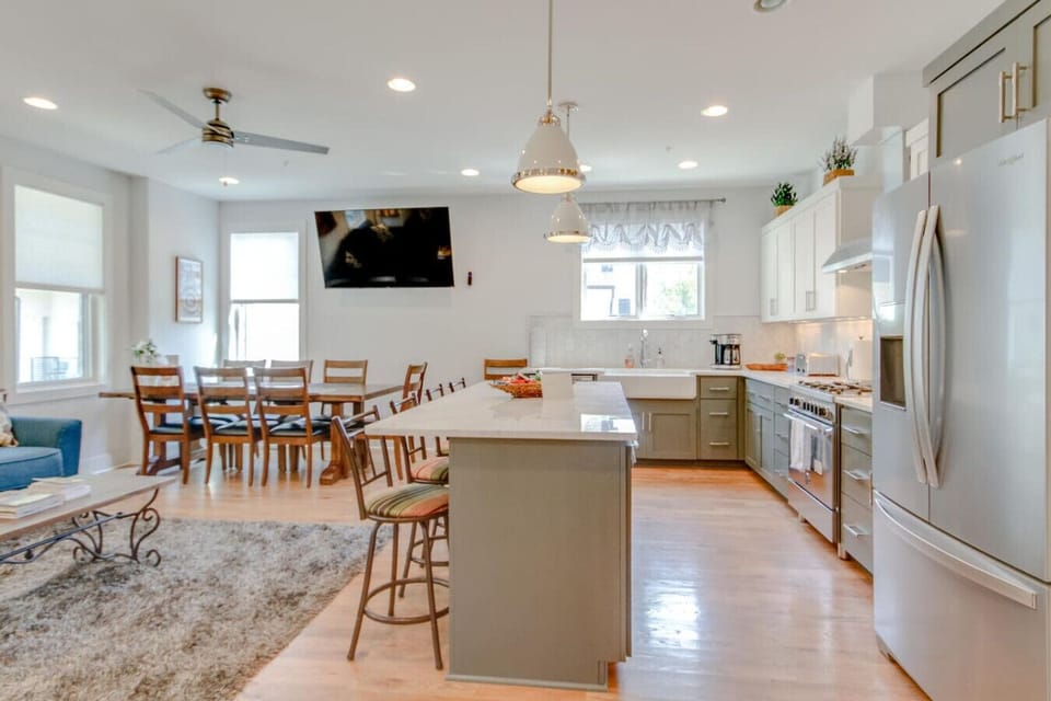Open kitchen and dining area with gray island, stainless steel range, and pendant lights