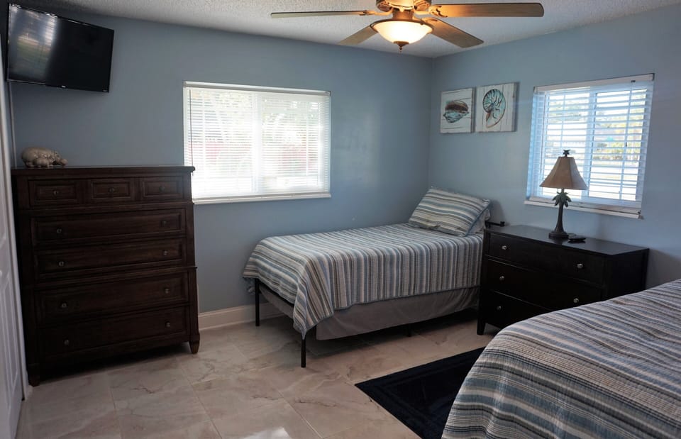 Cute bedroom, two twin beds, two dressers and wall mount smart TV. 