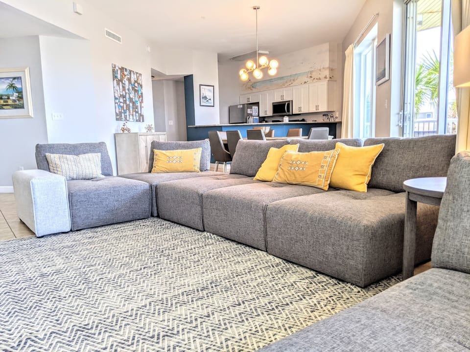 Gulf-View Living Room – Featuring a 60" TV and sectional sofa, Balcony Access