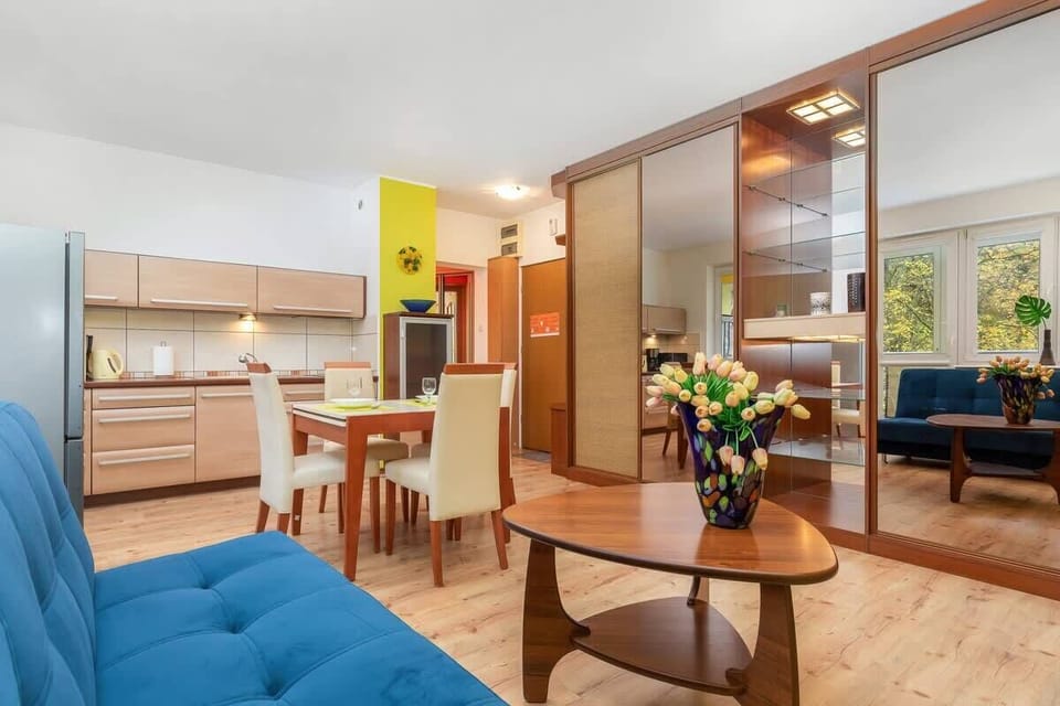 A view of the living room featuring a blue sofa, yellow accent wall, and a modern open-plan layout connecting to the dining area.