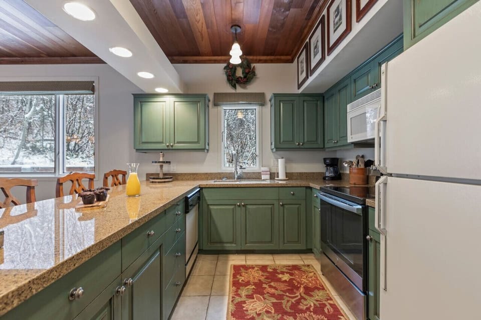 A gourmet kitchen with a large island with bar stools. Adjacent to the kitchen is an open dining area with a spacious table that seats up to 6. This space is ideal for entertaining and large gatherings, with ample natural light and mountain view