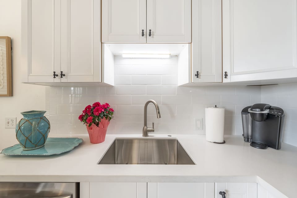"Chic white, stainless steel kitchen shines brightly, a chef's dream."