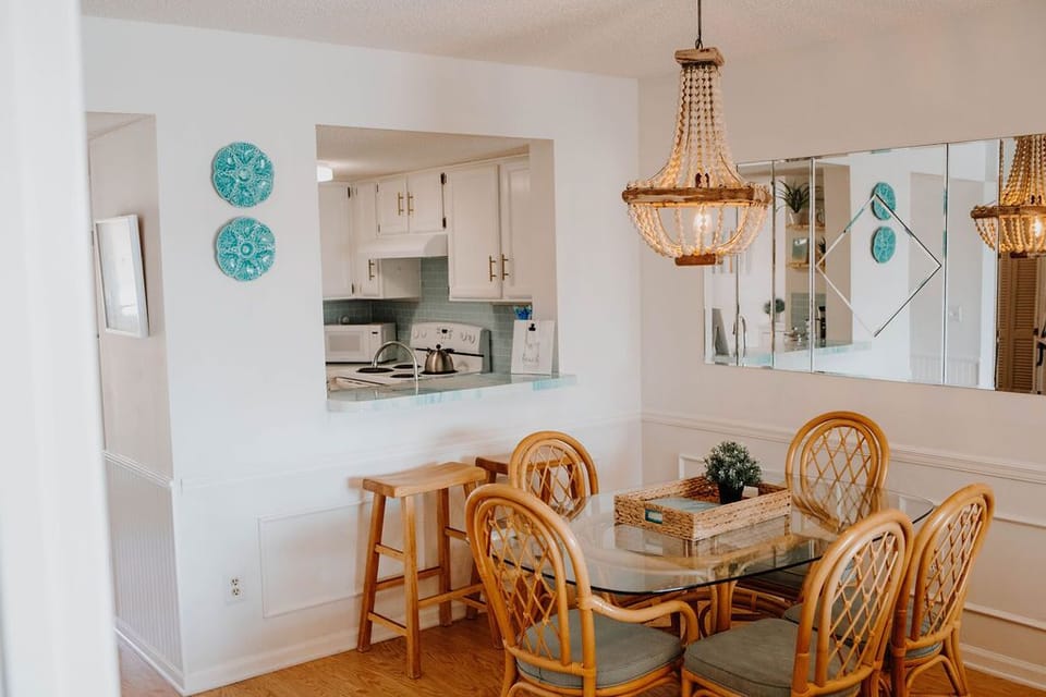 A driftwood and wood-bead chandelier hang over the beachy bamboo dining set