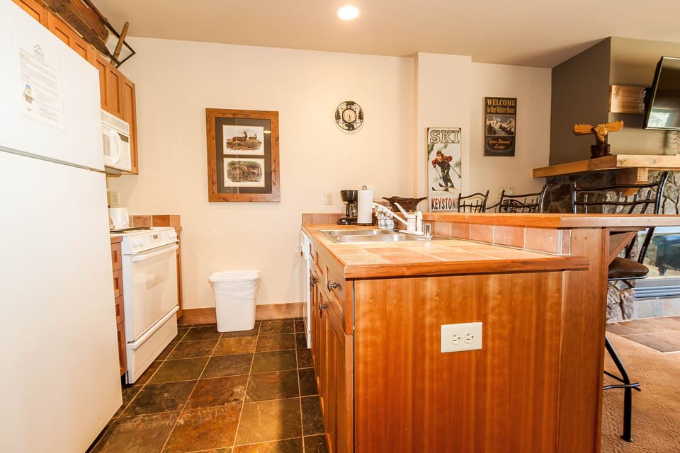 Your fully equipped kitchen features warm wood cabinetry, full-size appliances, and a charming breakfast bar perfect for morning coffee.