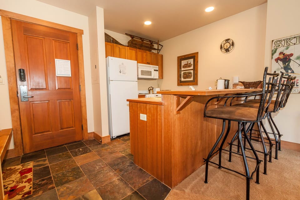 Your kitchen features warm wood cabinetry and a breakfast bar perfect for morning coffee or casual meals.