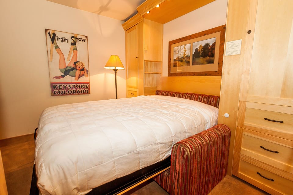 Cozy up in this thoughtfully designed bedroom featuring built-in storage and warm wood finishes that create your perfect mountain retreat sanctuary.