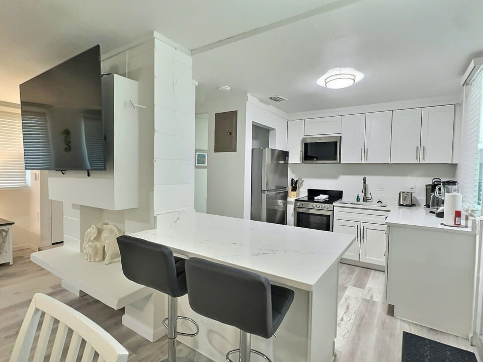 Updated kitchen with white cabinets, stainless appliances, and bar seating