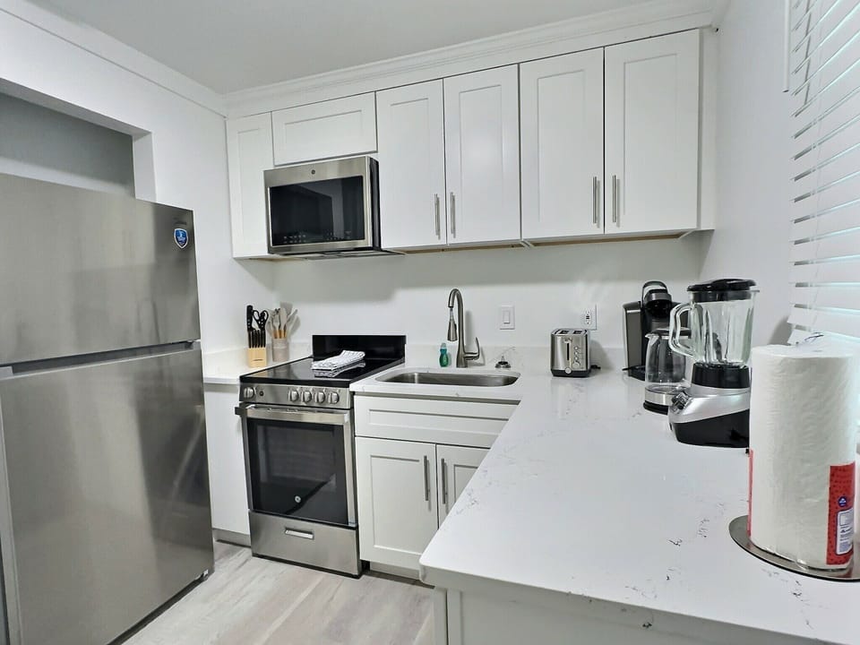 Kitchen with white upper cabinets, stainless refrigerator, range, and microwave