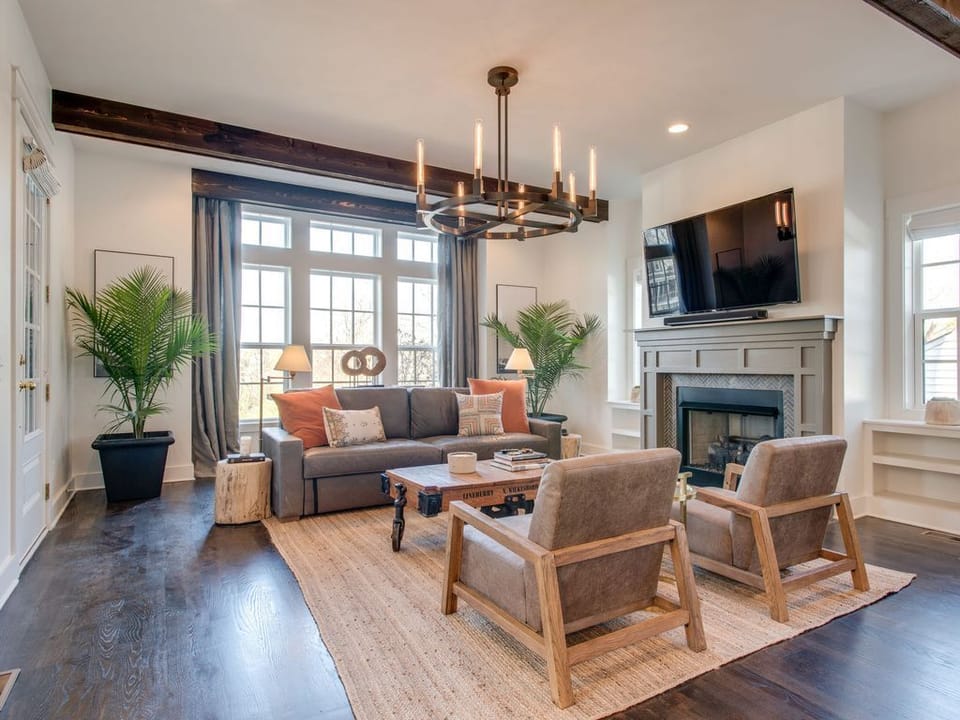 - Relax in this bright living room with modern seating and warm wood beams   - Enjoy the cozy fireplace and smart TV for a comfortable stay   - Large windows fill the space with natural light and charm