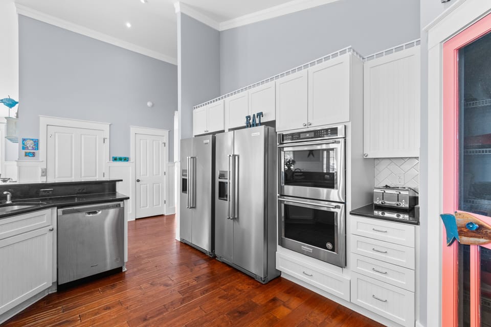 Your dream kitchen awaits with sleek stainless appliances, gleaming counters, and rich hardwood floors beneath soaring ceilings.
