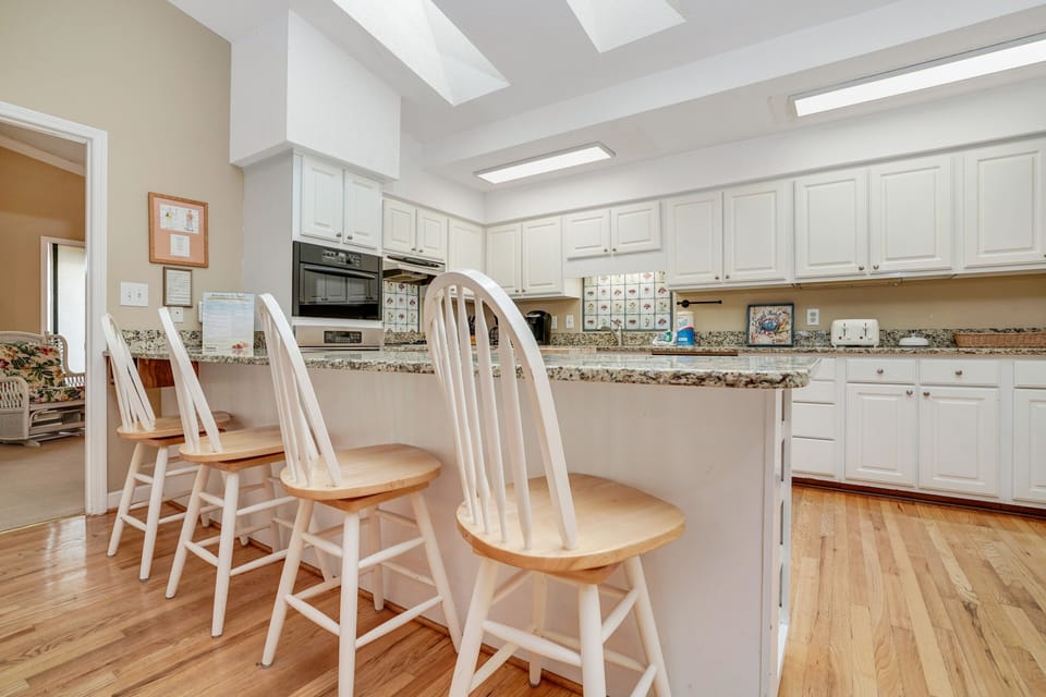 Your spacious kitchen awaits with granite counters, white cabinetry, and a breakfast bar perfect for morning coffee or meal prep.