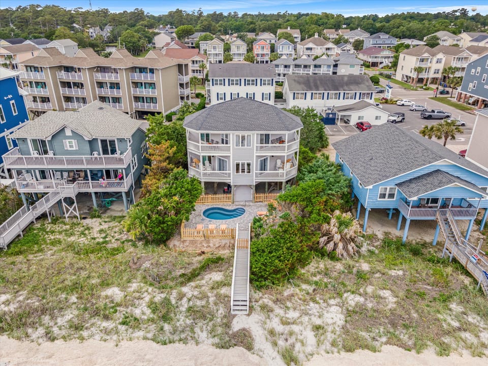 Coastal retreat featuring a private pool, elevated deck, and beachfront access surrounded by charming vacation homes.