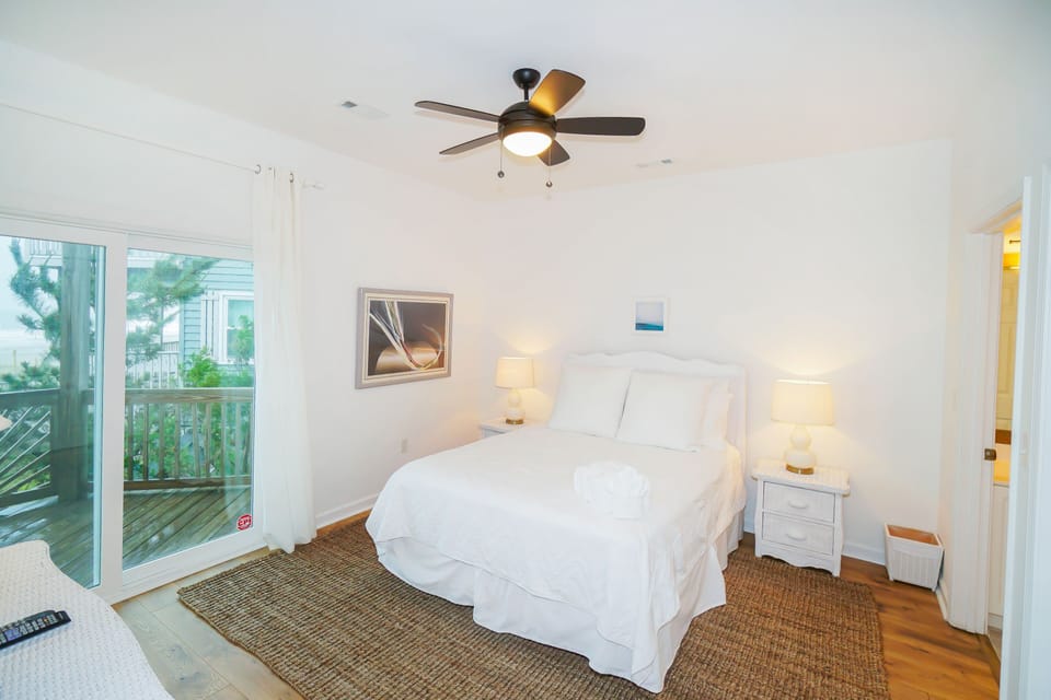 Drift off in your bright bedroom with crisp white linens and peaceful balcony views.