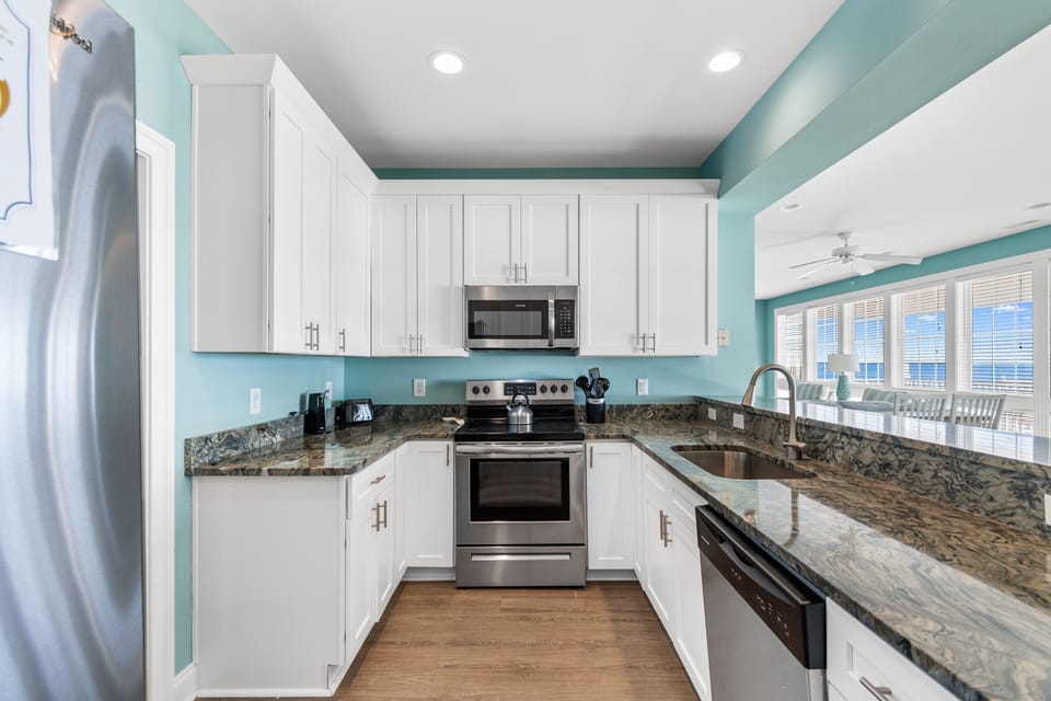 Step into this bright, fully-equipped kitchen where crisp white cabinets meet stunning granite counters, perfect for preparing meals together.