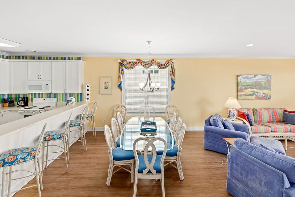 Your spacious open-plan living area seamlessly blends coastal comfort with modern convenience, featuring vibrant blue seating and a bright kitchen.