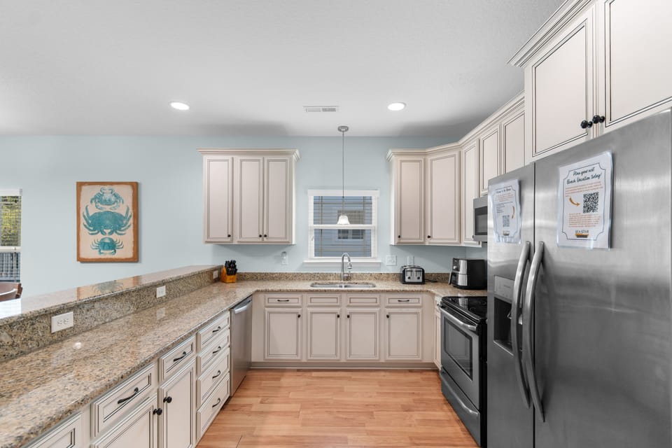 Your fully equipped kitchen features granite counters, stainless appliances, and coastal charm—perfect for preparing meals during your stay.