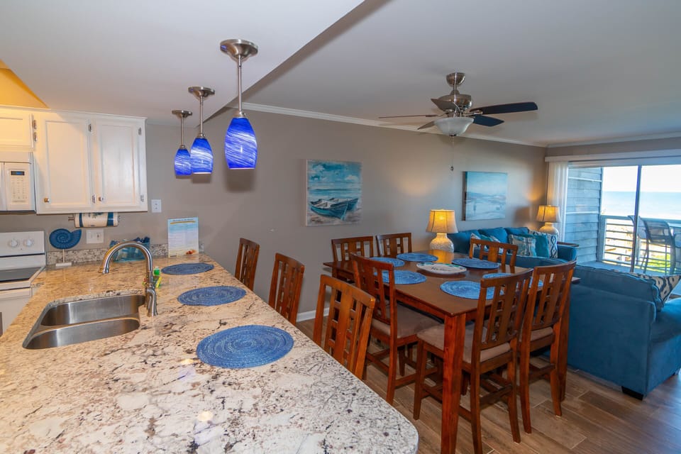 Gather around your spacious kitchen island and dining table, where ocean blues complement granite counters and sea views through sliding doors.
