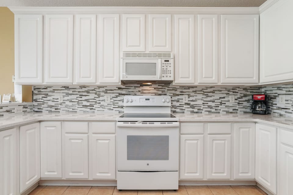 Your fully equipped kitchen features white cabinetry, mosaic tile backsplash, and modern appliances for comfortable meal preparation.