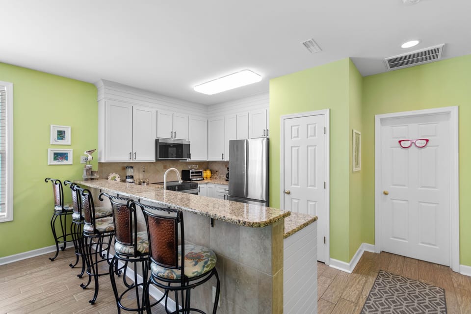 Gather around your breakfast bar with vibrant lime walls creating a cheerful cooking space that's perfect for morning conversations.
