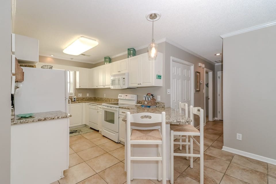 Your fully equipped kitchen features granite counters and breakfast bar seating, perfect for preparing meals and casual dining together.