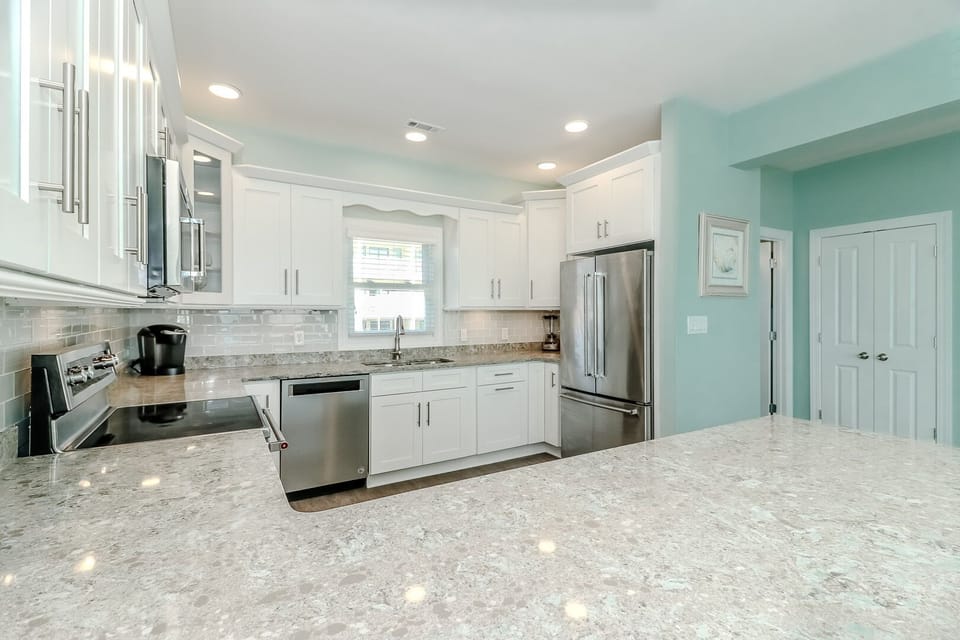 Your fully equipped kitchen features granite countertops, stainless steel appliances, and bright white cabinetry perfect for preparing meals together.