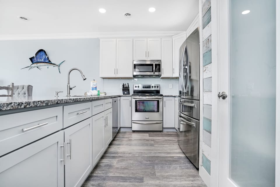 Your fully equipped kitchen awaits with granite counters, stainless appliances, and coastal charm to inspire memorable meals together.
