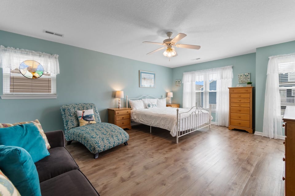 Unwind in your spacious bedroom with soothing seafoam walls, cozy seating, and gentle ceiling fan breezes.