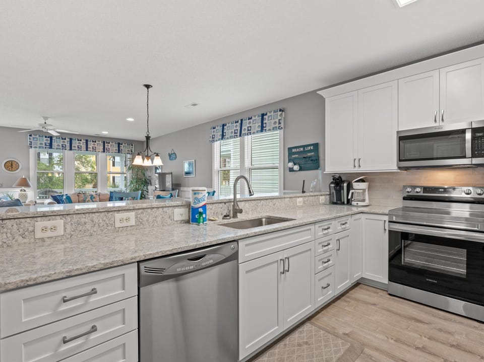 Cook memorable meals in your fully-equipped kitchen with granite counters, stainless appliances, and natural light streaming through cheerful blue valances.