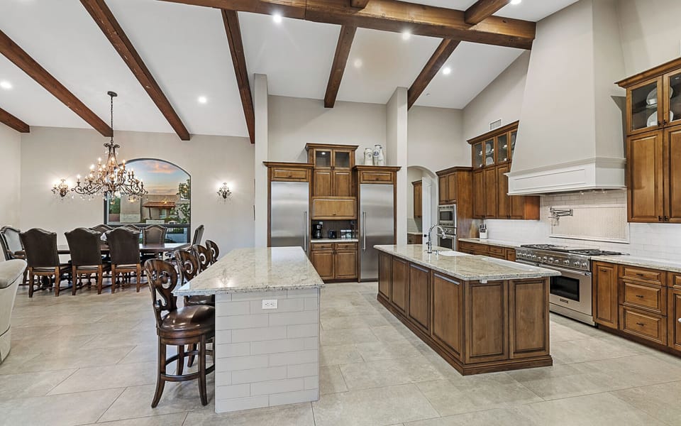 Chef’s kitchen with double islands, gas range, fridge, and great room access
