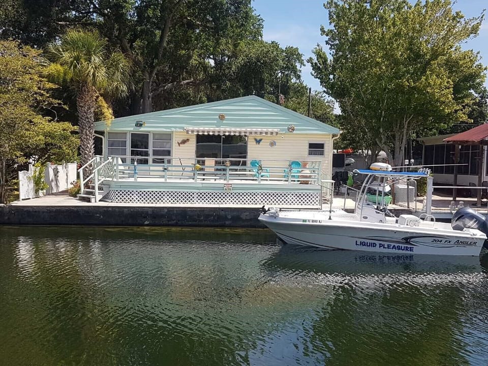 The outdoor deck with tables, chairs, and fire pit faces the river.