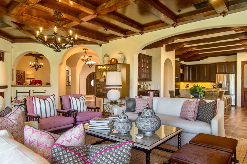 Welcome to your sanctuary of serenity! This chic living room w/ high wooden ceilings dazzling fireplace seamlessly melds contemporary design, perfect for intimate evenings, all while offering captivating views of the pool, garden, and mountains.