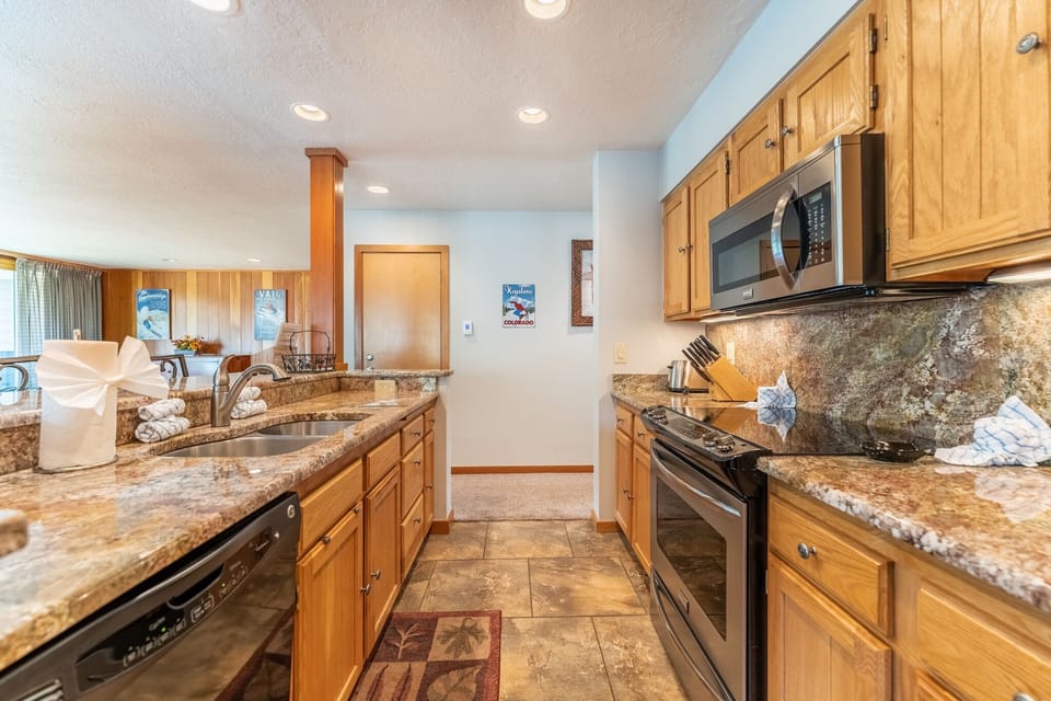 Full size kitchen with granite countertops and stainless steel appliances.