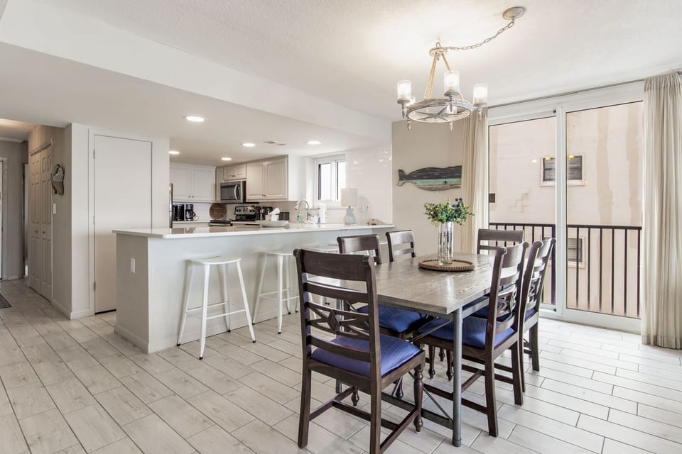 Dining and kitchen area with white finishes at Wind Drift Orange Beach