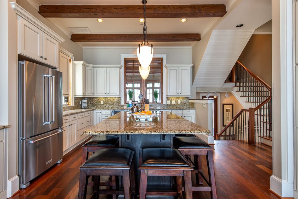 Kitchen Island with Stools, Refrigerator, and Stairwell.