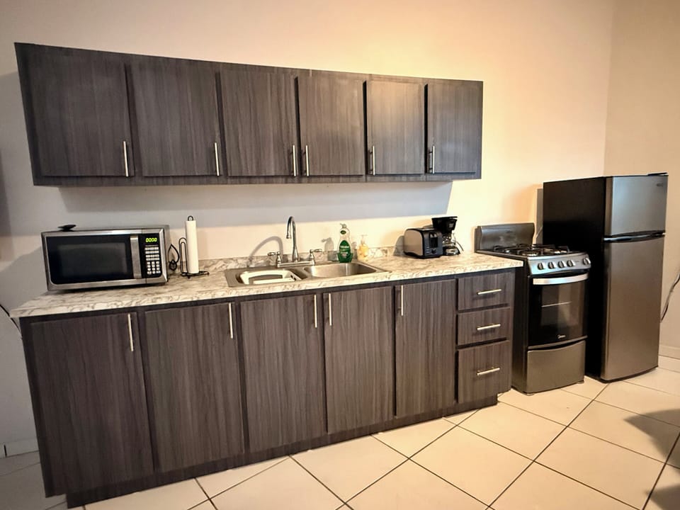 The kitchen area includes microwave, toaster, coffee maker, stove, refrigerator 