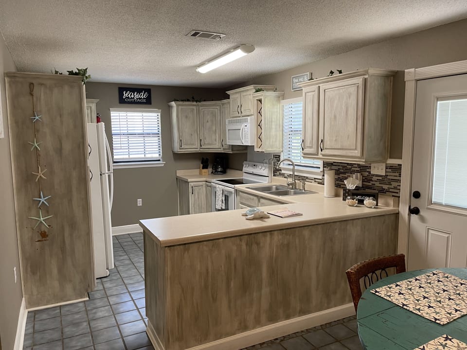 full kitchen with lots of custom chalk painted cabinets and large counter top