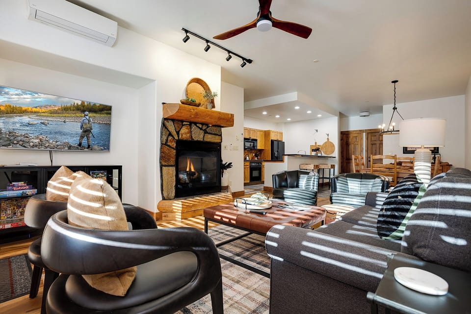 Sink into plush seating by the crackling fireplace as natural light streams through, creating the perfect mountain retreat atmosphere.