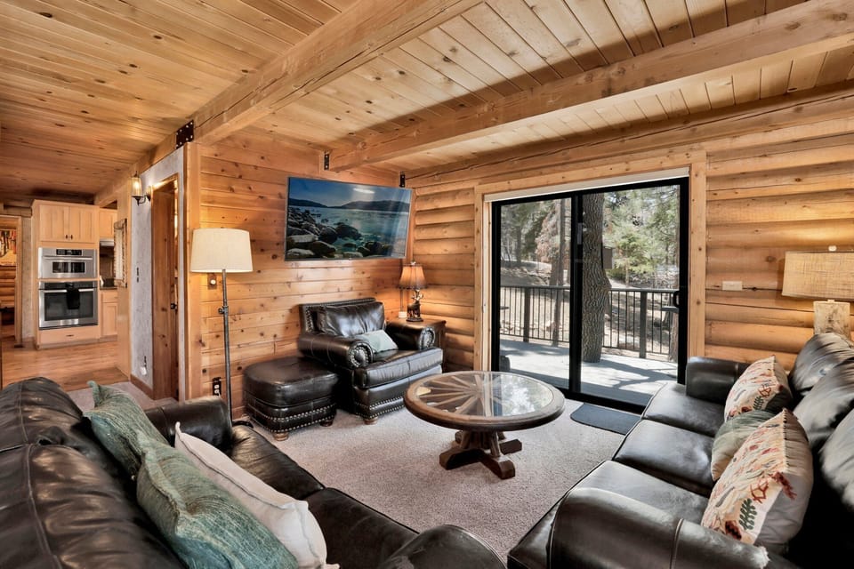 Cozy mountain living room with a stone fireplace, comfy seating, and smart TV—perfect for relaxing evenings, movie nights, and warm cabin vibes after outdoor adventures.