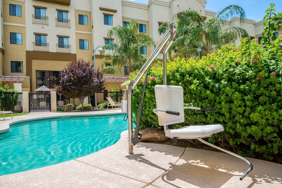Accessible outdoor pool with pool lift and lounge chairs.