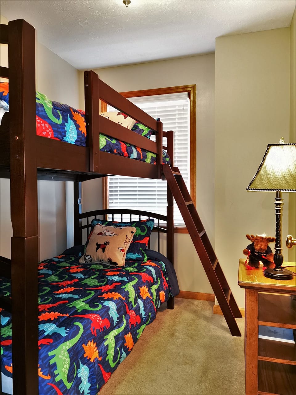 Cozy kids' room with bunk beds and colorful dinosaur-themed bedding